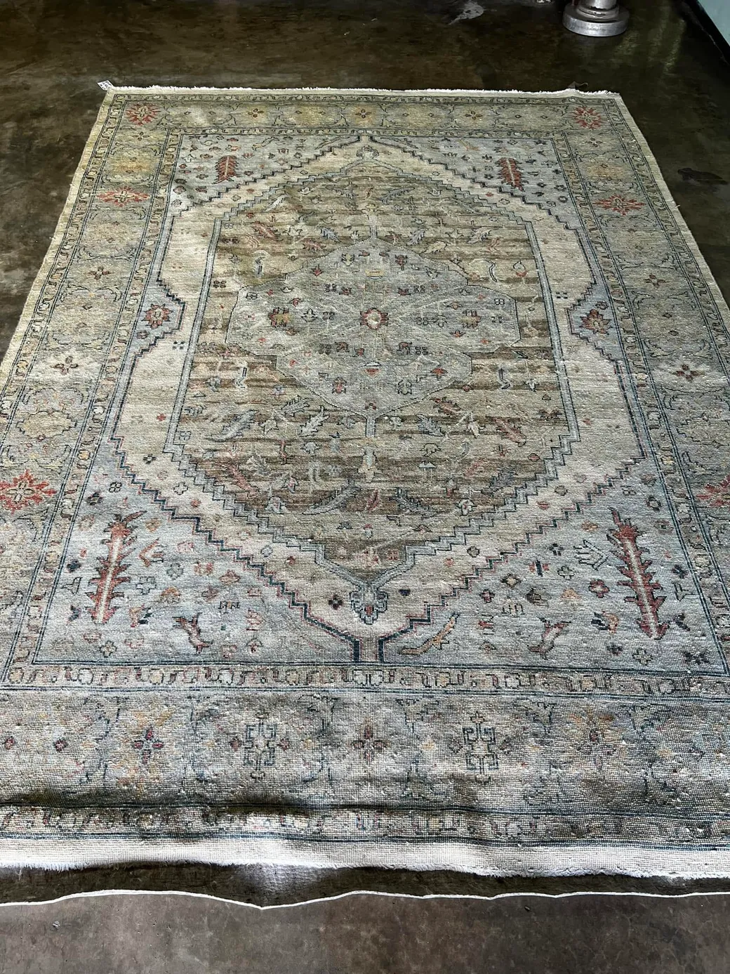 A freshly washed antique Persian rug laid out on the plant floor in Sarasota